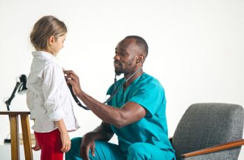 The healthcare and medical concept - african male doctor with stethoscope listening to child chest in hospital. The doctor, health, medicine, patient, pediatrician, illness concepts